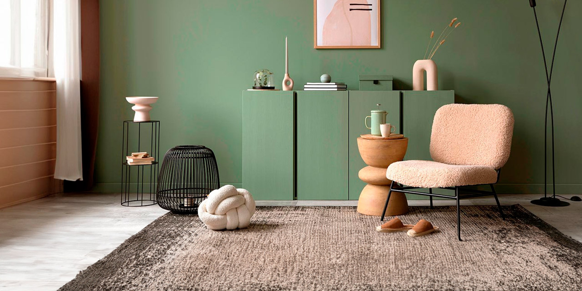 Mueble bajo en color verde con jarrón y sofá color crema