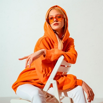 Chica rubia sentada en una silla con sudadera naranja