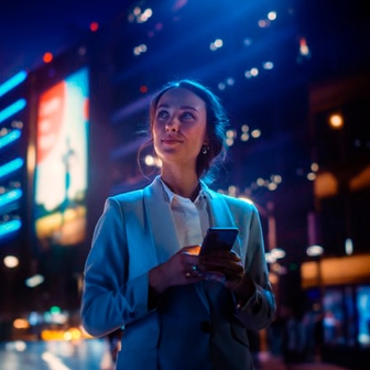 Chica de negocios en la calle con móvil en la mano