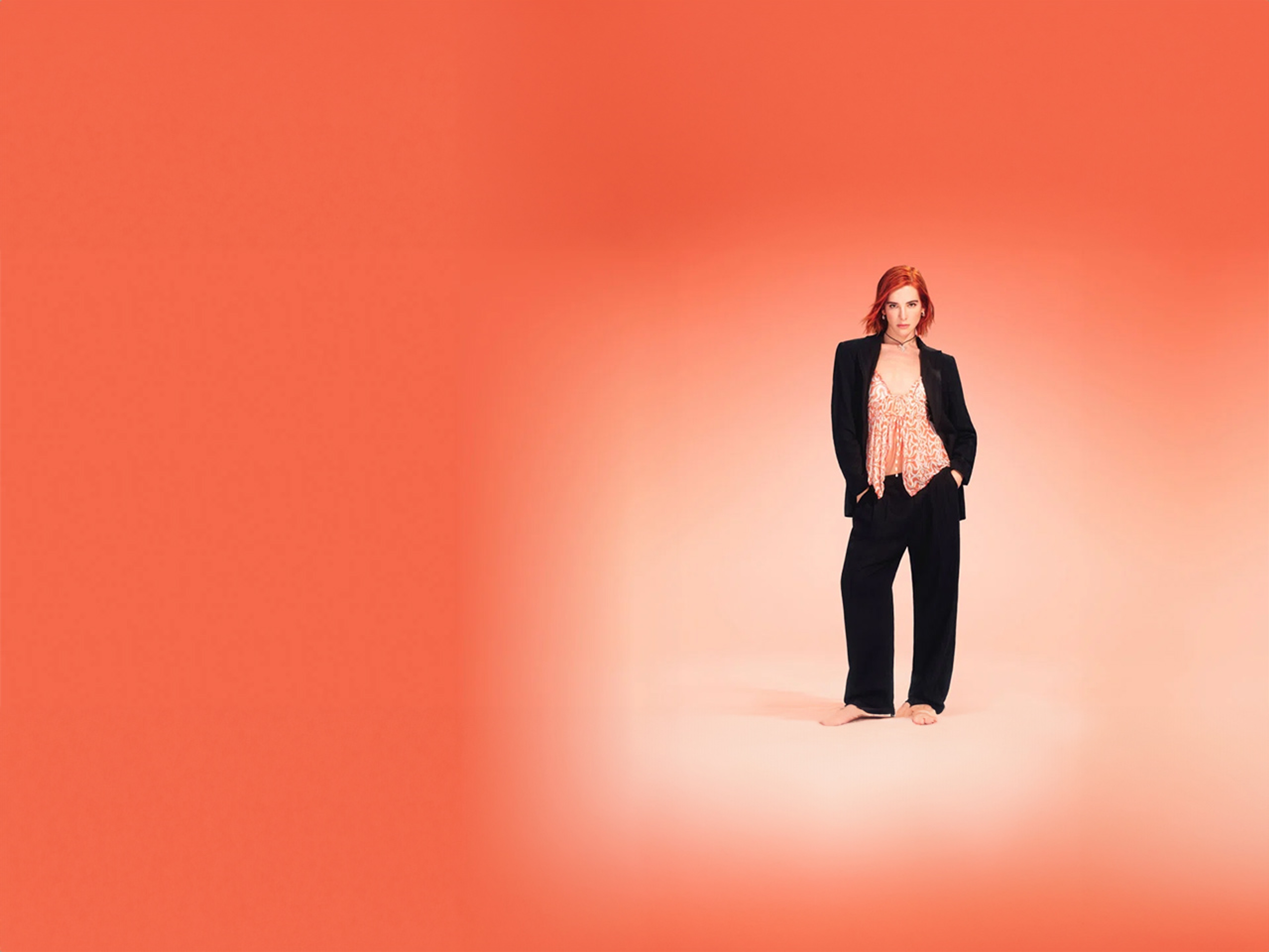 Chica con traje negro y top en color naranja sobre fondo naranja