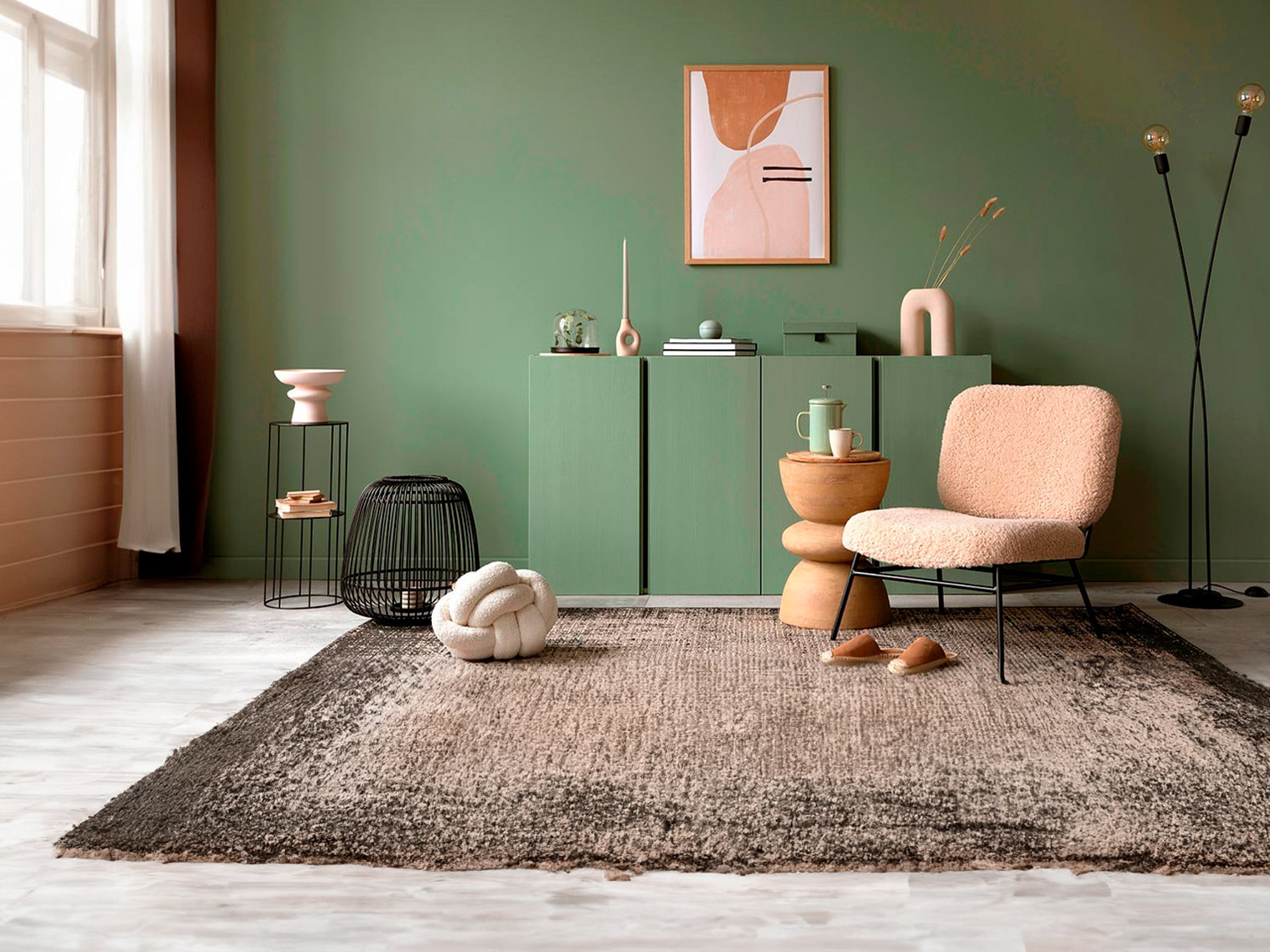 Mueble bajo en color verde con jarrón y sofá color crema