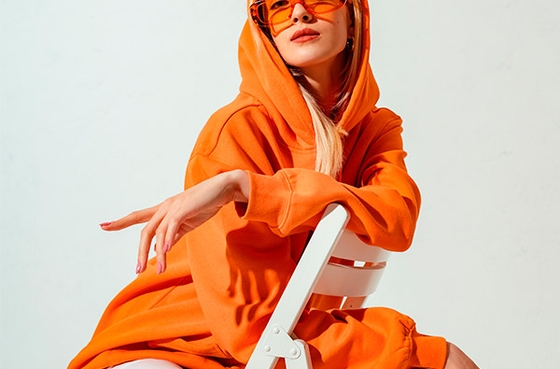 Chica rubia sentada en una silla con sudadera naranja